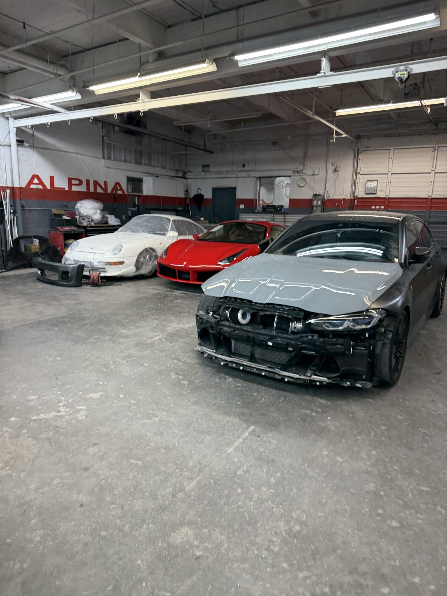 A BMW stripped for collision repair beside a red Ferrari in the Alpina bay, Southeast Portland