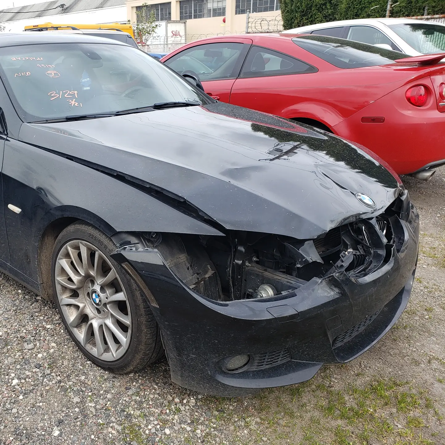 A black BMW 3 Series coupe with heavy front-end collision damage before repair at Alpina